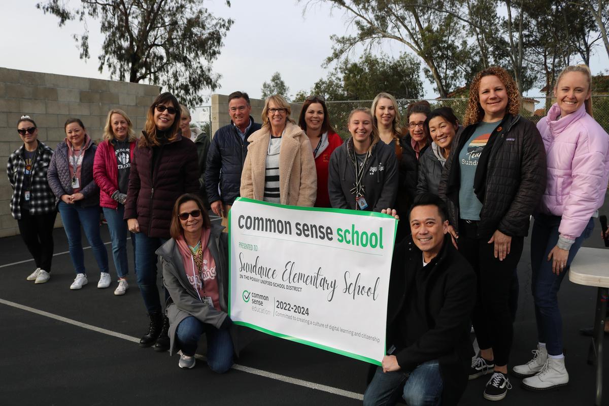 students and staff posing with common sense banner